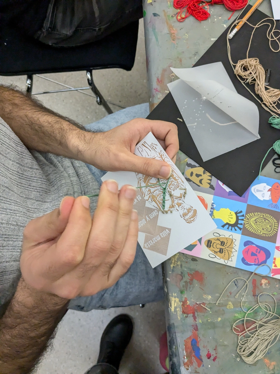 Hands embroidering on a postcard during workshop