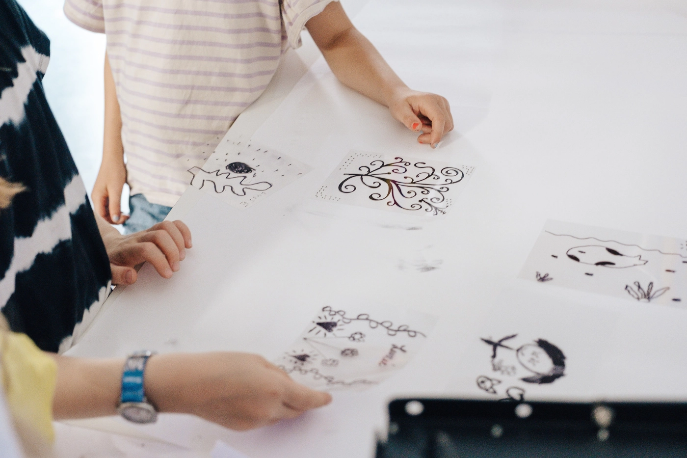 Children arranging their ink drawings on transparent film over the light table before the cyanotype exposure