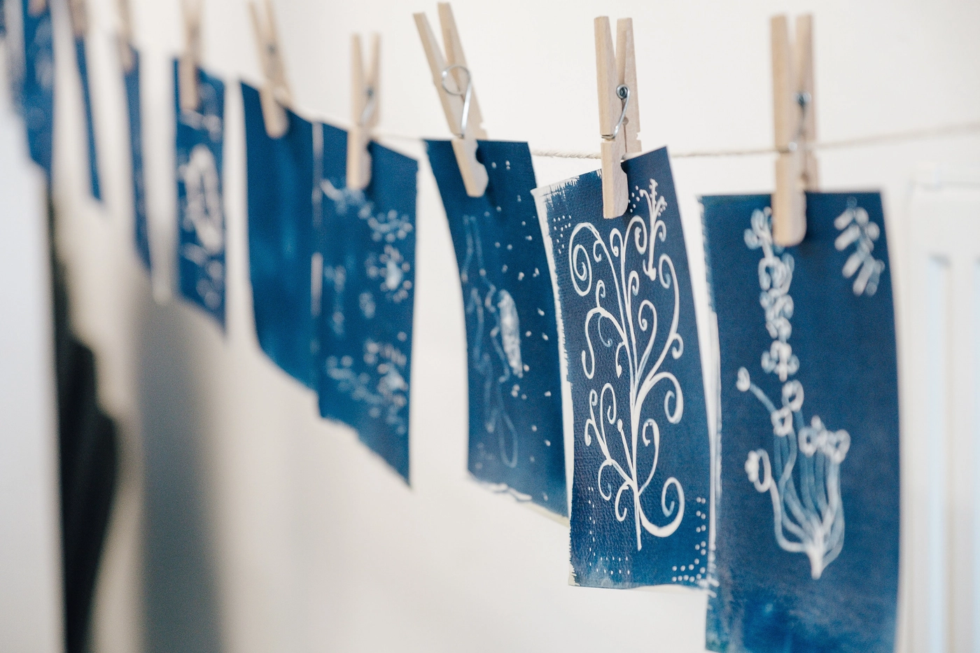 Cyanotypes from the week pegged to a line with wooden clothespins, hanging up to dry
