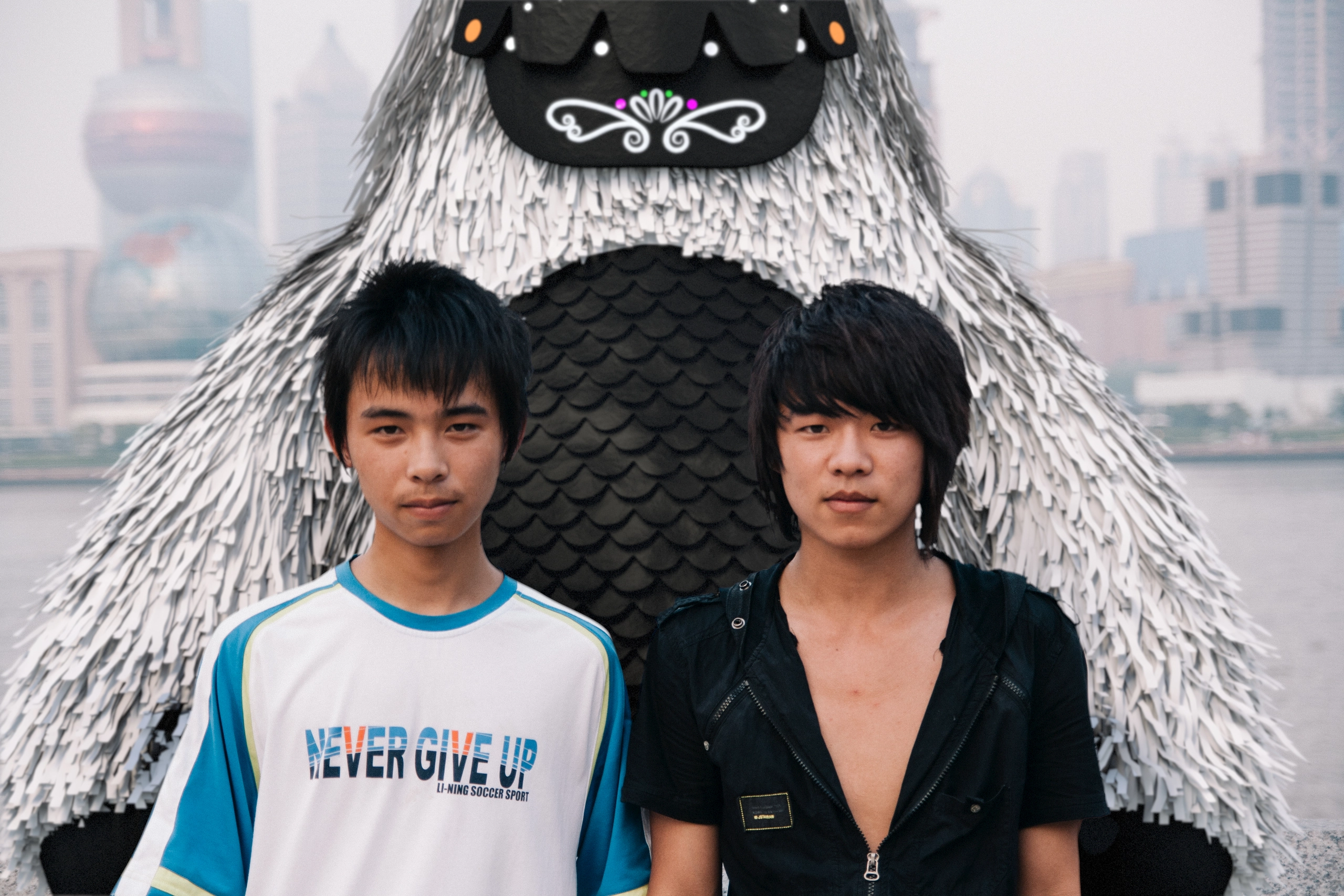 A sidewalk along the river in Shanghai. Two young men posed for their own photograph nearby, neither one looking his way.